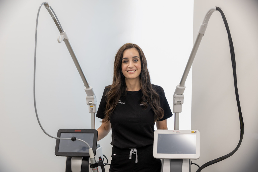 Whitney standing between the two Lutronic devices at the Elite clinic